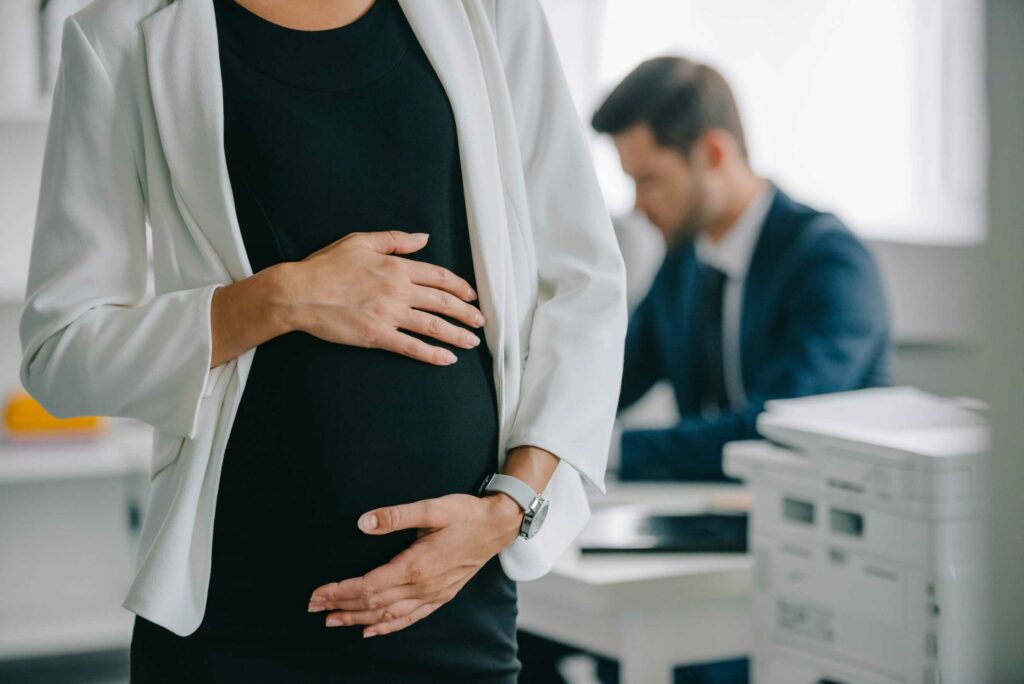 Pregnant woman at work holding her stomach